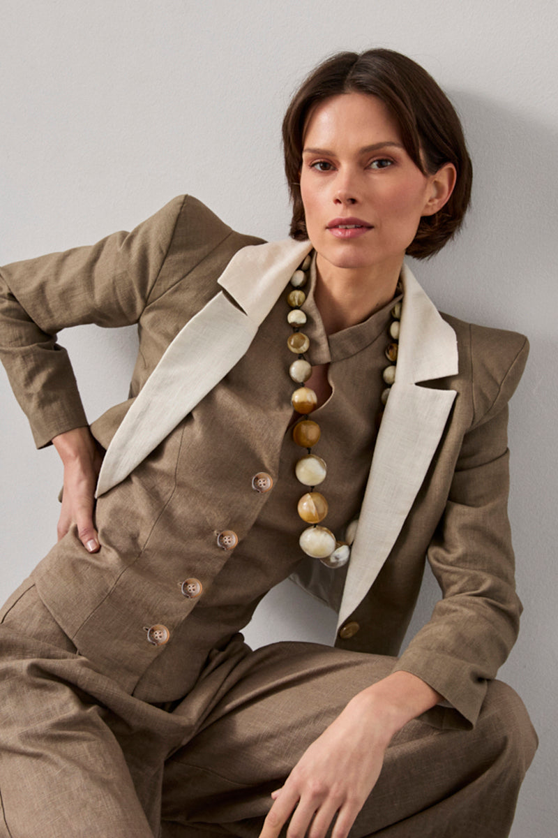 Chaqueta con hombreras en color verde caqui y solapa a contraste en color crema. Está forrada y se cierra con dos botones en el delantero.