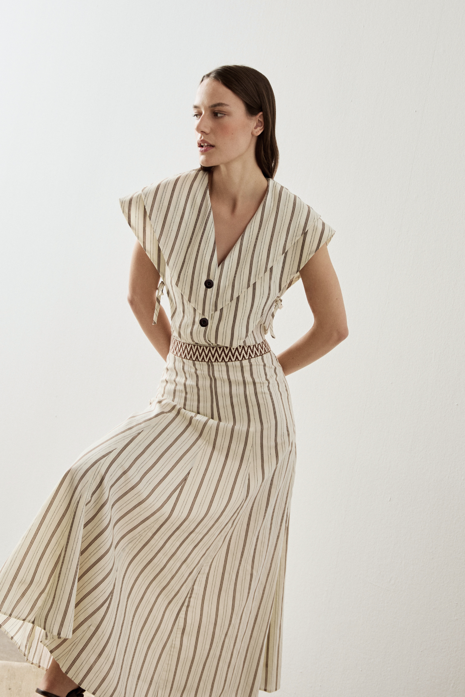 Top de manga corta en color crudo con rayas y escote en uve. Este top cuenta con capas superpuestas y tiene detalle con lazada en el lateral.