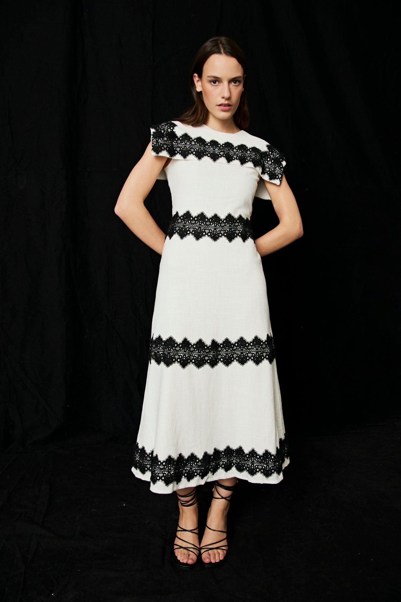 Vestido midi en color blanco con detalles de pasamaneria en negro.