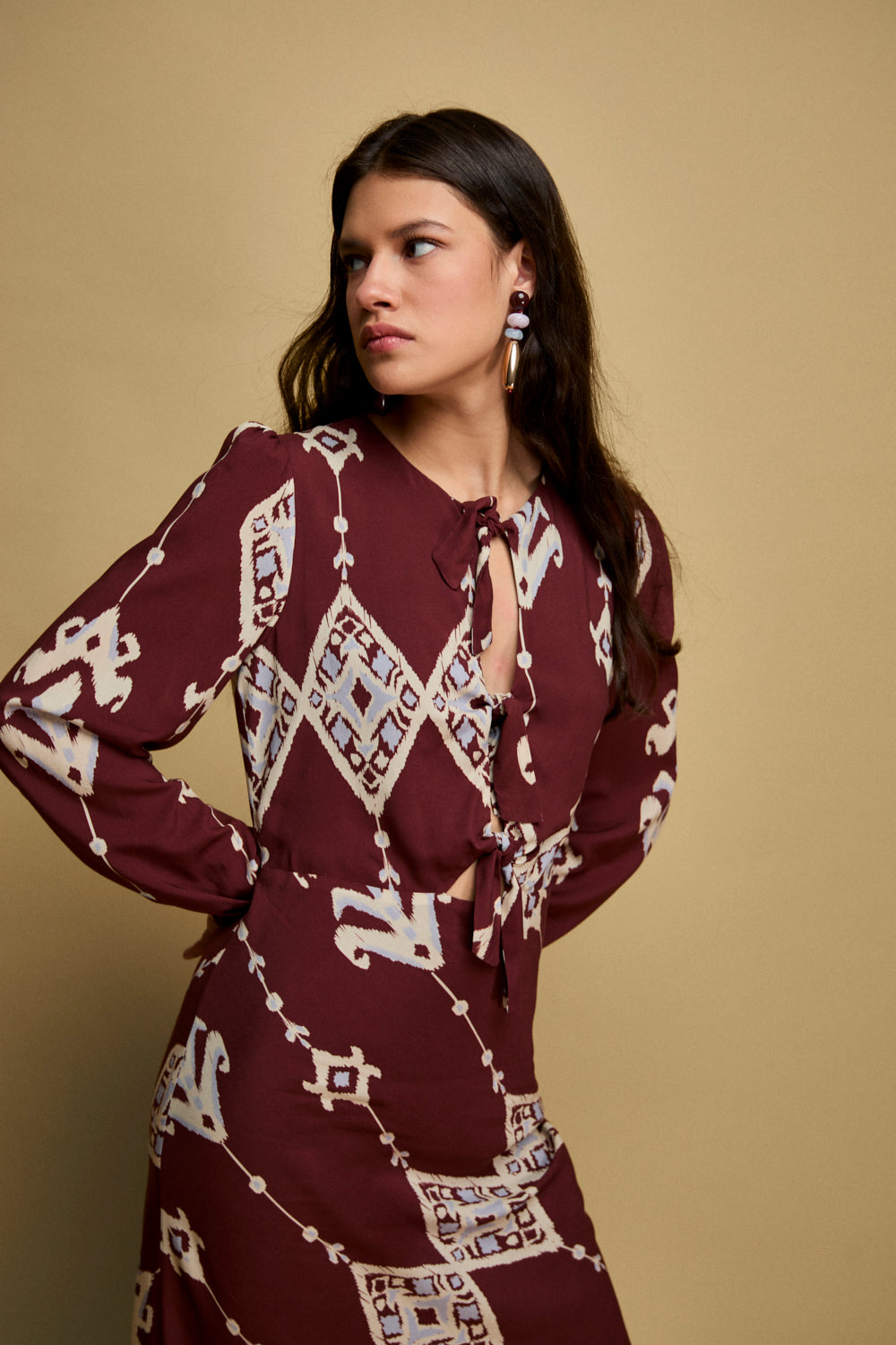 Vestido midi en color burdeos con escote a la caja y manga larga.Este vestido tiene corte en la cintura con lazadas en la parte frontal y falda con corte evasé.